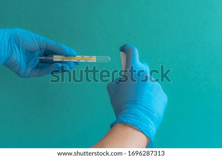 Women's hands in gloves with a thermometer, hands in gloves, women's hands, blue medical gloves, antiseptic treatment of a medical thermometer