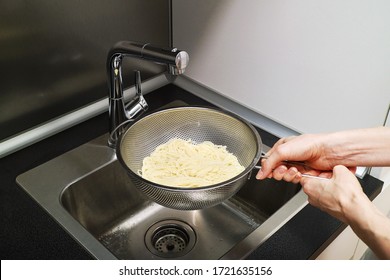 Women's hands hold a colander with noodles over the sink to drain the water for cooking delicious Italian pasta       - Powered by Shutterstock