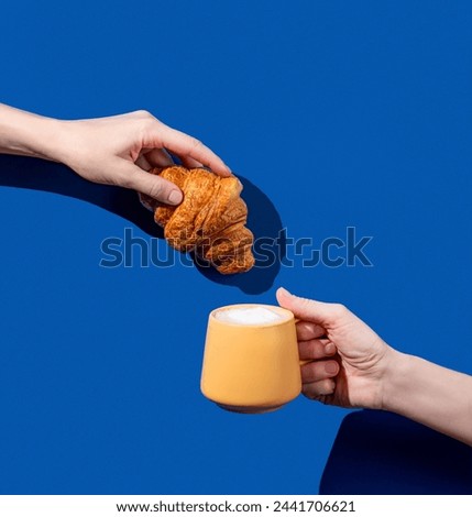 Women's hands hold fresh croissant and cup of coffee  on a blue background. Design concept for breakfast pastry mockup or banner. Free space fot text. Stock fotó © 
