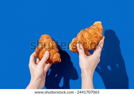 Women's hands hold fresh croissants on a blue background. Design concept for breakfast pastry mockup or banner. Free space fot text. Stock fotó © 