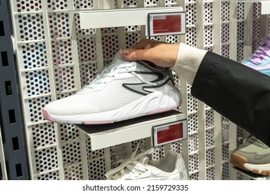 Women's Hands Hold A New Sneaker Taken From The Shelf Of Sports Store