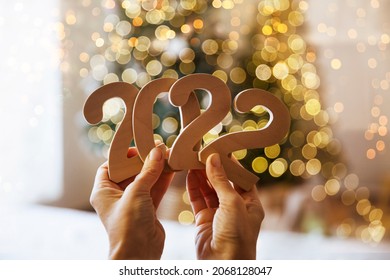 women's hands hold numbers 2022 against the background of Christmas decor
