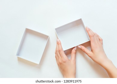 Women's Hands Hold A Small White Box On A White Background, Top View