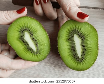 Women's hands hold two halves of kiwi. Sliced kiwi. Background. The benefits and harms of kiwi. Vitamin C. Sour fruits. Slices of kiwifruit. - Powered by Shutterstock