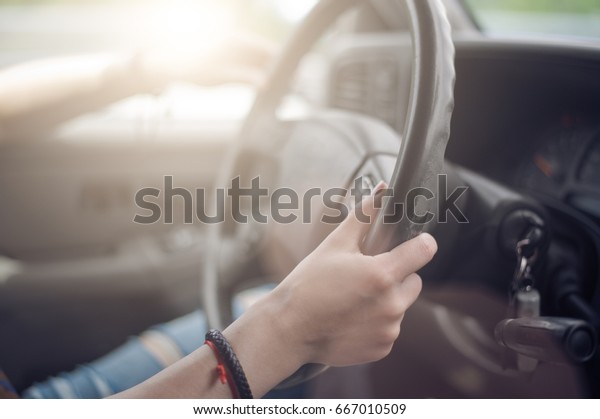 Women\'s hands hold the\
wheel of a car
