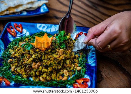 Women's hands holding baby clams with rice crackers, they are decorated on wooden table  - specialty food at  Da Nang, Viet Nam