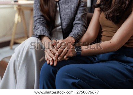 Women's hands interlocking, offering empathy, comfort, and care to a friend