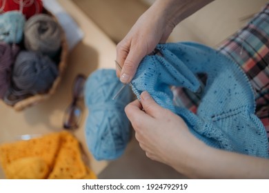 Les mains des femmes tricotées et filées. Gros plan. Femme en bonneterie assise sur un canapé