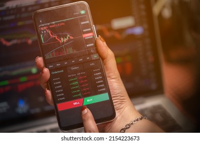 Women's hands are looking at data and making arbitrage trading on cryptocurrencies market on smart phones. - Shutterstock ID 2154223673