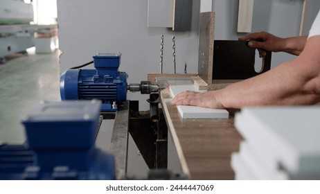 Women's hands make a hole in the panel of a furniture factory. Close-up of a hole in a wood panel using a drill press. A drilling machine makes a hole in an MDF panel. About to drill a hole. - Powered by Shutterstock