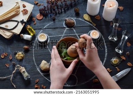 Womens hands make love potion on pentagram circle with candles, stones and old books on witch table. Occult, esoteric or divination concept. Mystic, Halloween and vintage background