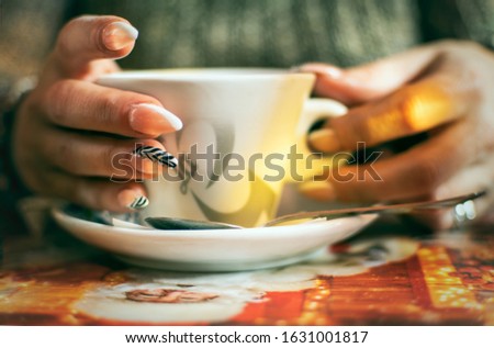 Women's hands with manicured nails holds cup of coffee