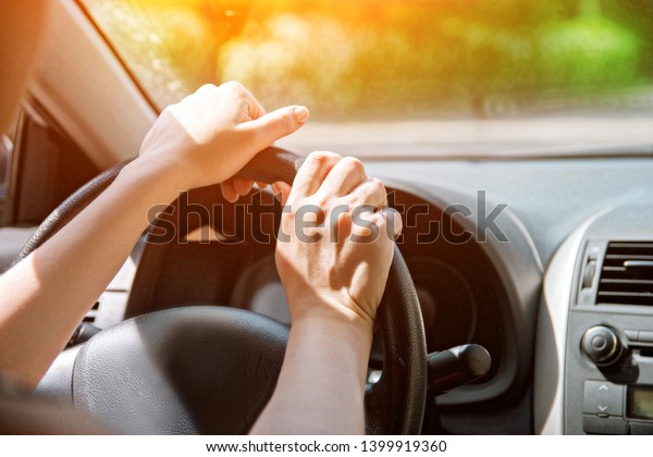 Women\'s hands on the wheel.\
Close up.