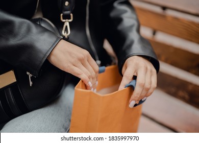 Women's Hands Opens A Bag From The Store, Looks At What She Bought. Black Leather Jacket, Color Bags