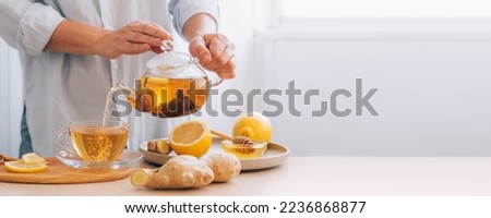 Women's hands pour hot drink ginger root tea lemon from teapot for cold treatment and prevention