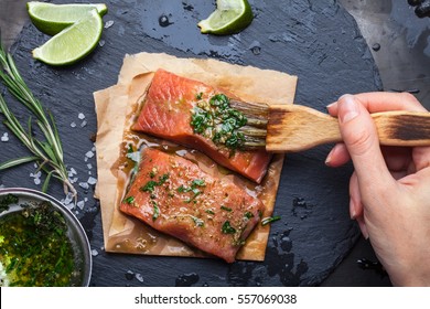 Women's Hands Are Preparing Salmon Shale Rock On A Dark Metallic Background. View From Above. Preparation For Cooking Fish Food. Salmon Steak. Woman Cook.