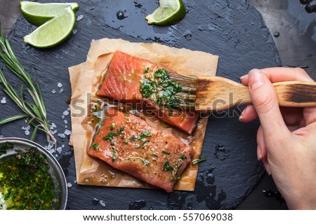 Women's hands are preparing salmon shale rock on a dark metallic background. View from above. Preparation for cooking fish food. Salmon steak. Woman cook.