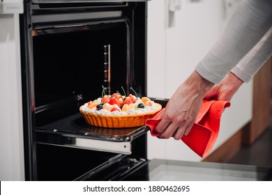 Women's hands reach for a beautiful, freshly made berry pie from the oven in a white modern kitchen. - Powered by Shutterstock