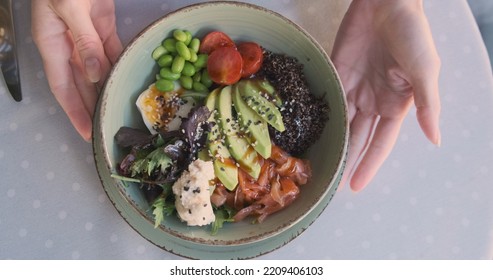 Women's Hands Turn A Plate With A Bowl In A Restaurant, Standing On A Table. Top View, Close-up. The Concept Of Healthy And Wholesome Food