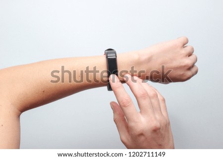 Women's hands use smart watch on gray background. Modern gadgets, top view
