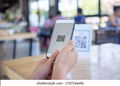 Women's hands are using  the phone to scan the qr code to select food menu. Scan to get discounts or pay for food. The concept of using a phone to transfer money or paying money online without cash. - Shutterstock ID 1747166696