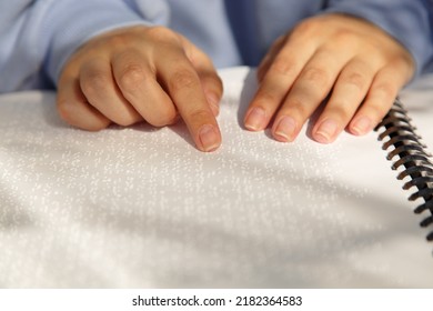 Women's Hands With Violet Sleeves On Book In Louis Braille Font