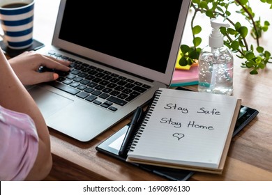 Women's hands working at home, with a computer and a stay safe sign, stay home. antibacterial gel, coffee
