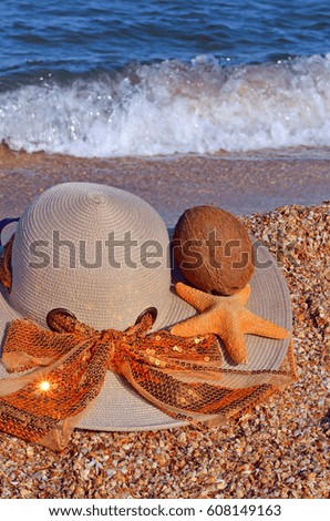 Women's hat, coconut and starfish on the beach.