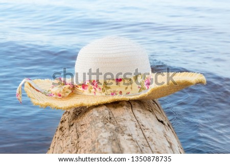 Women's hat with wide brim on a log on the water