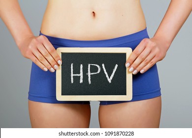 Women's health concept. Young woman holds a small chalkboard with "HPV" inscription