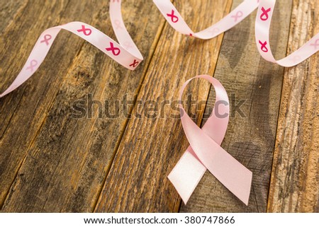 Womens health symbol in pink ribbon on wooden board.