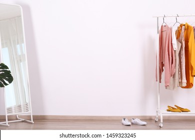 Women's Hip Clothing Store Interior Concept. Row Of Different Colorful Female Clothes Hanging On Rack In Hipster Fashion Show Room In Shopping Mall. Grunged Concrete Wall Background. Copy Space.