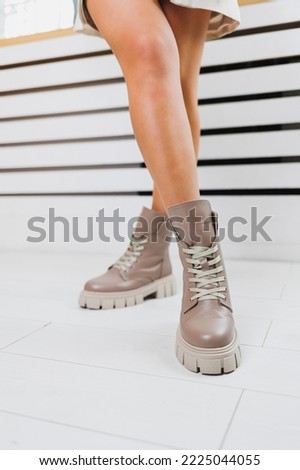 Women's leather shoes. Slender female legs in beige leather boots. Fashionable women's boots.