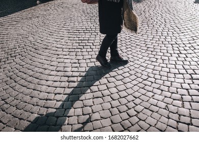 Women's legs in black jeans and winter boots walk along gray granite paving stones and casts a contrasting shadow.. The concept of a walk in the old city. - Shutterstock ID 1682027662