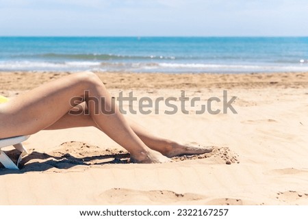 Women's legs close-up, the girl is relaxing on the beach in a sun lounger, enjoying the sun on a sunny summer day. seaside vacation concep