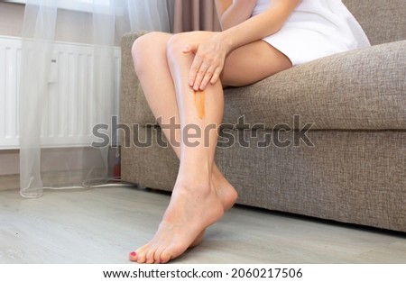Women's legs with a drop of self-tanning lotion. A girl in her apartment puts bronzer on her legs after a shower on her legs after a shower