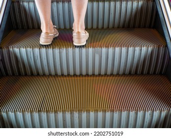 Women's legs standing on escalators stairway.