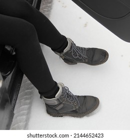 Women's Legs In Winter Boots Get Out Of The Car On A Snowy Road Close Up Biew