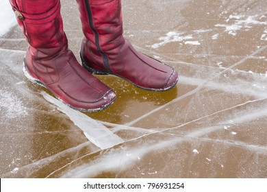 Women's Red Leather Winter Boots On The Cracked Ice Surface. First Steps On The Thin Ice At The Shore. Dangerous Concept.