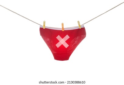 Women's red panties with a cross hanging on a clothesline, white background, isolate. Concept of proctological diseases in women
