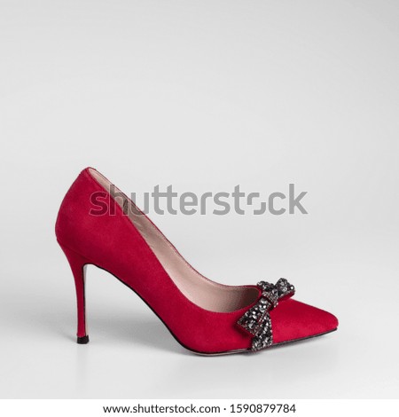 womens red suede high heel shoes with a decorative bow from rhinestones on a toe on a white background in studio for a catalog