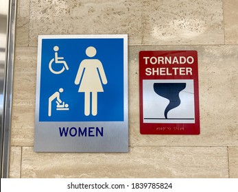 The Women's Restroom And Tornado Shelter Signs Directing People To The Shelter In A Public Building.