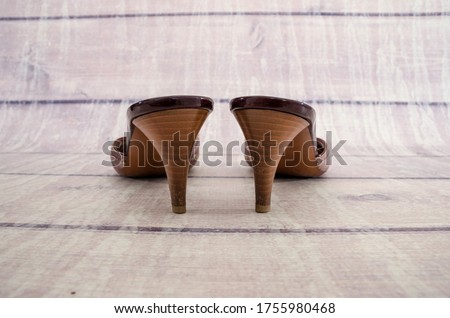 Women's sandals on a wooden background. Fashionable summer sandals. Back view. Heels close-up.