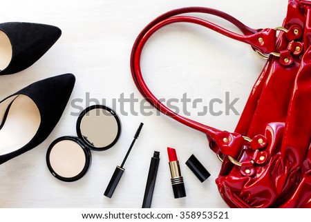 Women's set of fashion accessories on wooden background: shoes, handbag and cosmetics