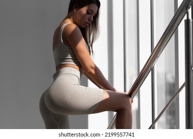 Women's Sportswear In Gray On A Beautiful Slim Model. Sportswoman Posing At The Panoramic Window