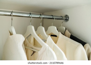 Women's Sweaters And White Shirts Hang In The Closet. Outdated Clothes In The Home Wardrobe. Close-up