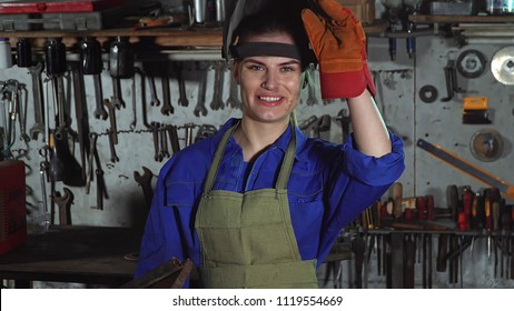 Women's work cute girl welder in uniform in the garage in the background of the workbench . - Powered by Shutterstock