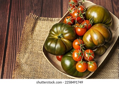 A wonderful basket full of ripe tomatoes on a light brown burlap cloth - Shutterstock ID 2258491749