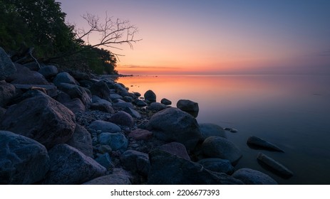 wonderful colorful sunset on a calm sea with a rocky shore - Shutterstock ID 2206677393