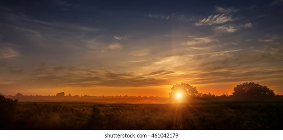 wonderful dramatic scene. fantastic foggy sunrise over the meadow with colorful clouds on the sky. picturesque rural landscape, misty morning. color in nature. beauty in the world - Powered by Shutterstock